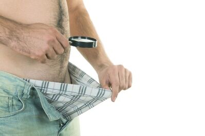 Ein Mann schaut auf seinen Penis und möchte ihn vergrößern.